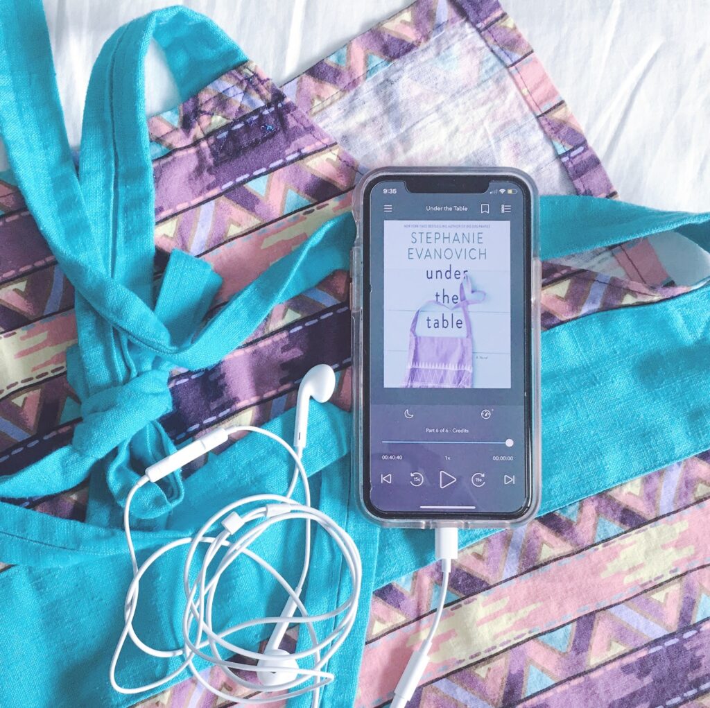 Audiobook of Under The Table by Stephanie Evanovich on top of an apron